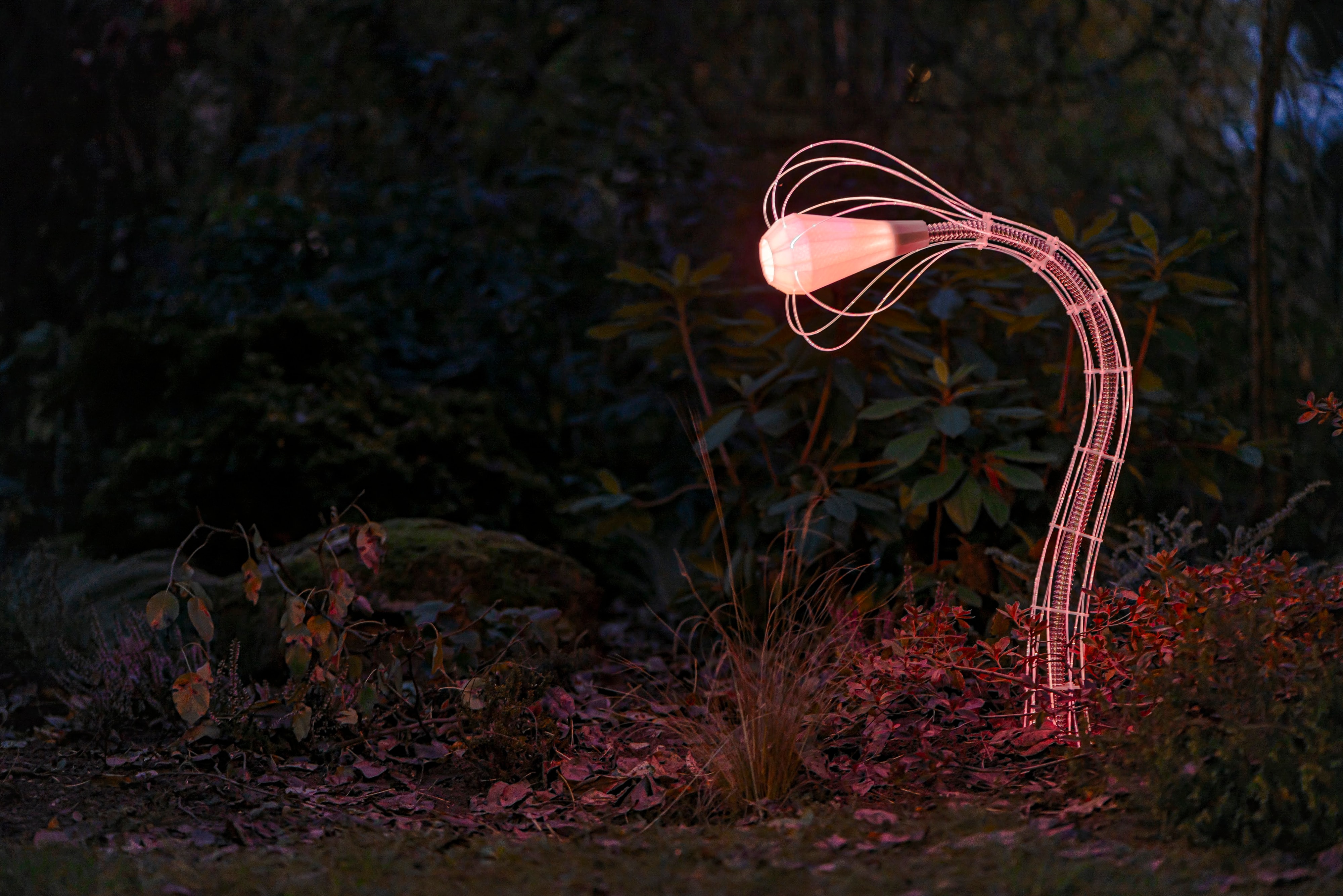 IXFID — venkovní zakřivená zahradní lampa svítící teplou růžovo-oranžovou v noci