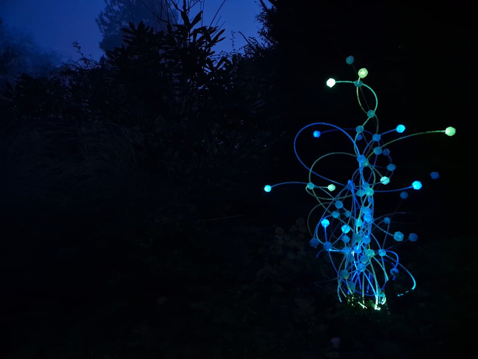 Sculpta — azurová svítící venkovní socha s hexagonálními uzly v noci